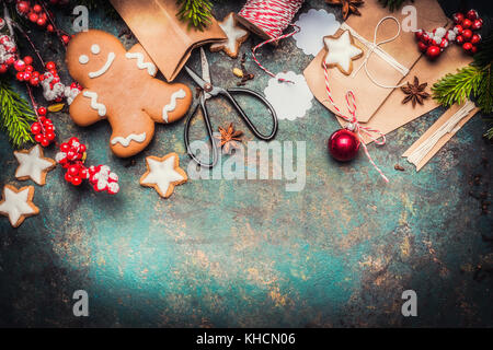 Regali di natale la fasciatura con gingerbread man, star cookies, cesoie e artigianale di scatole di cartone su sfondo vintage, vista dall'alto, di confine Foto Stock