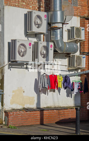 Una parete esterna di unità di condizionamento dell'aria con una linea di coloratissimi lavaggio asciugatura sotto, centro città, Northampton, Regno Unito Foto Stock