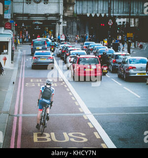 Un ciclista il pendolarismo in corrispondenza di un incrocio occupato nella zona di London Bridge. Londra, 2017. Formato quadrato. Foto Stock