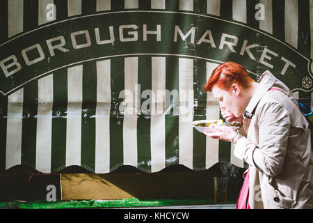 Una donna con un pasto nel mercato di Borough. Londra, 2017. Formato orizzontale. Foto Stock