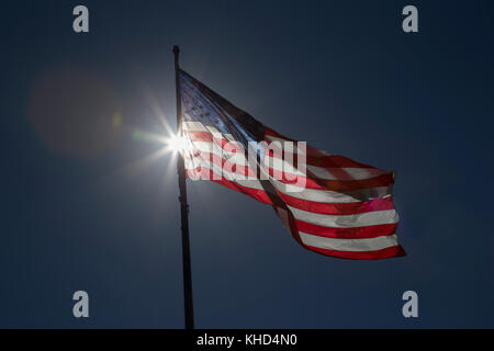 Bandiera americana retroilluminazione contro un profondo cielo blu Foto Stock