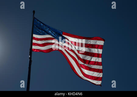 Bandiera americana retroilluminazione contro un profondo cielo blu Foto Stock