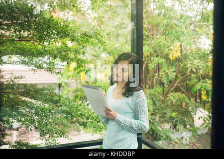 Giovane attraente ragazza dolce con notepad su una veranda. La molla dell'umore. Foto Stock