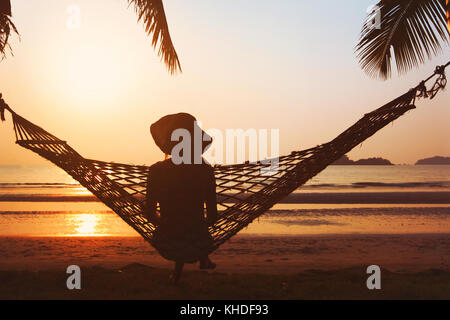 Relax sulla spiaggia, donna in amaca godendo bellissimo tramonto tropicale