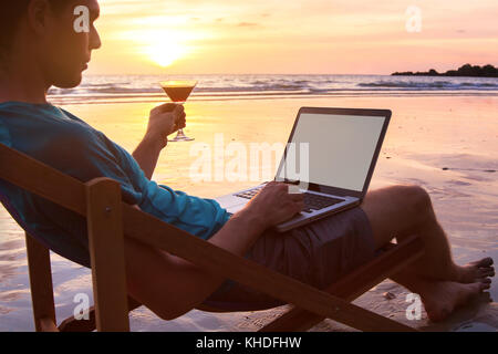 Imprenditore di successo freelancer lavorando sul computer del Sunset beach, laptop con schermo vuoto e copyspace Foto Stock