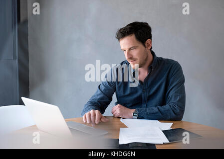 Uomo che utilizza il computer portatile in ufficio Foto Stock