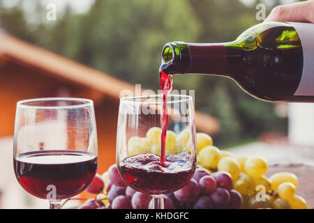 Close up di vino rosso che viene versato dal flacone di vetro Foto Stock