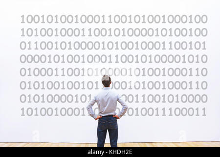 Programmatore uomo guardando il codice binario, il concetto di codifica, la crittografia dei dati Foto Stock