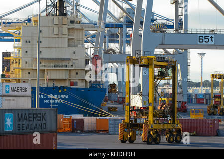 Auckland, Nuova Zelanda - 17 aprile 2012: Nave, straddle carrier, gru gommate e la pila di contenitori ad Auckland porta a mare. Foto Stock