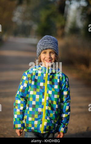 Ritratto di un sorridente ragazzo di 9-10 anni. Il ragazzo è vestito con una camicia colorata e un cappuccio a maglia. Foto Stock