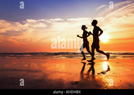 In esecuzione in background, sport e allenamento, sagome di persone fare jogging a Sunset beach Foto Stock