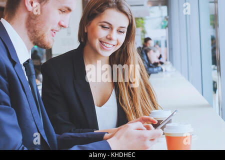 Sorridente la gente di affari utilizzando lo smartphone e di bere il caffè Foto Stock