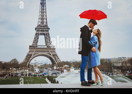 Romantico affettuoso giovane baciare sotto ombrellone vicino alla Torre Eiffel, luna di miele a Parigi Foto Stock