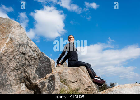 Attività sportive donna seduta sulle rocce Foto Stock