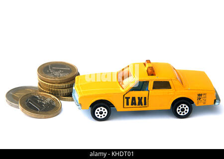 Taxi toy isolato accanto alle monete metalliche in euro. Foto Stock