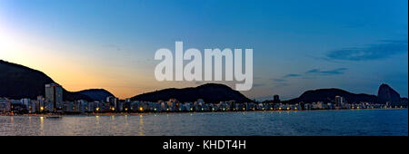 La notte arrivando dietro le colline di Copacabana beach con i suoi edifici, luci, il mare e la collina di Sugar Loaf Foto Stock