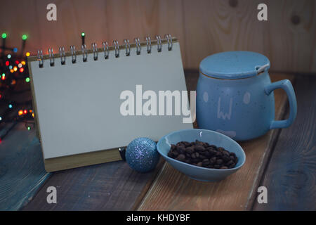 Aprire il notebook, blue cup e chicco di caffè in una ciotola sul tavolo Foto Stock