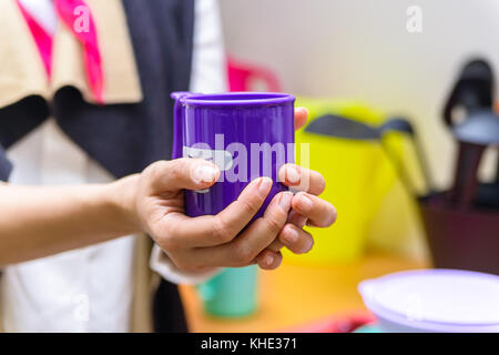 Tenere le mani una tazza di plastica con il volto sorridente Foto Stock