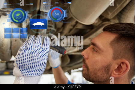 Uomo meccanico con torcia a riparazione auto in negozio Foto Stock