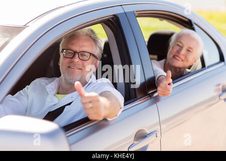 Coppia senior guida in auto e mostrando pollice in alto Foto Stock