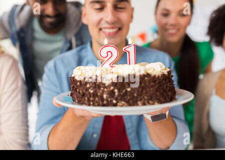 Uomo con torta e amici alla festa di compleanno Foto Stock