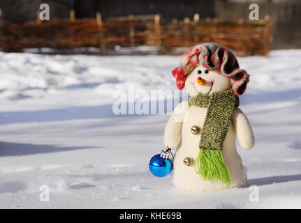 Toy pupazzo di neve con natale giocattolo in mani in piedi nella neve Foto Stock