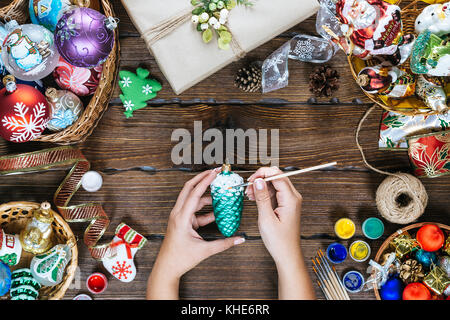 Decorazioni di Natale, sfere, giocattolo e confezioni regalo su una vecchia tavola di legno. mani femminili trarre nuovo Anno decorazioni. bella cornice con spazio libero. idea fo Foto Stock