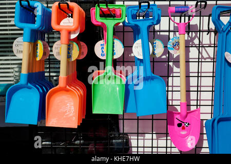 Vivacemente colorato giocattolo di plastica picche appeso sul display al di fuori di un negozio a Lyme Regis nel Dorset. Foto Stock