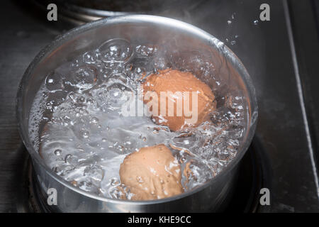 Le uova in acqua bollente nella casseruola sul piano di cottura elettrico Foto Stock