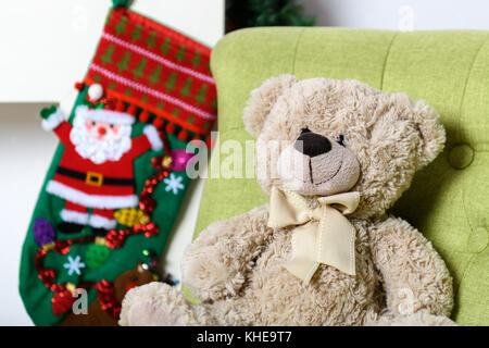 Orsacchiotto di peluche in una sedia sotto l albero di natale Foto Stock