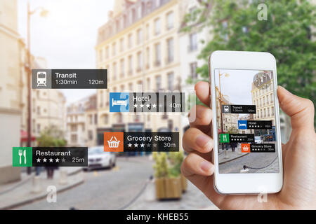 Le tecnologie informatiche di realtà aumentata (AR) relative alle attività e ai servizi nelle vicinanze sullo schermo dello smartphone guidano i clienti o i turisti in città, close-u Foto Stock
