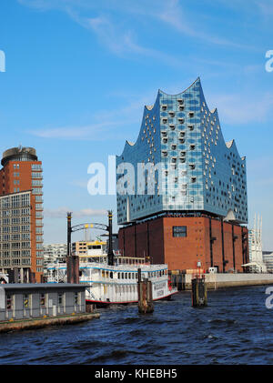 Vista dal porto inferiore attraverso il fiume Elba su Elbphilharmonie. Il nuovo punto di riferimento di Amburgo contiene sale da concerto, un hotel e appartamenti ed è stata progettata dagli architetti svizzeri Herzog e De Meuron, Amburgo, Germania Foto Stock