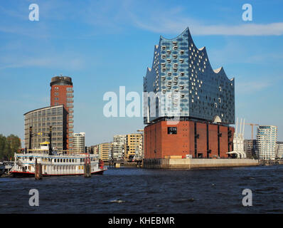 Vista dal porto inferiore attraverso il fiume Elba su Elbphilharmonie. Il nuovo punto di riferimento di Amburgo contiene sale da concerto, un hotel e appartamenti ed è stata progettata dagli architetti svizzeri Herzog e De Meuron, Amburgo, Germania Foto Stock