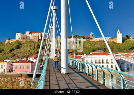 Donna che attraversa il moderno ponte pedonale verso il centro storico di Alcacer do SAL, Alentejo, Portogallo Foto Stock