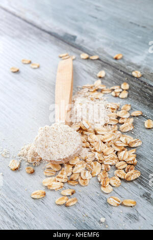 Farina di avena in cucchiaio di legno con fiocchi di avena su un tavolo di legno. senza glutine concetto. Foto Stock
