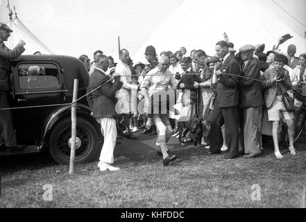 Re Giorgio vi indossa pantaloncini corti con una sigaretta in mano al campo estivo del Southwold Boys Club al Duke of York Camp. 3 agosto 1937 Foto Stock