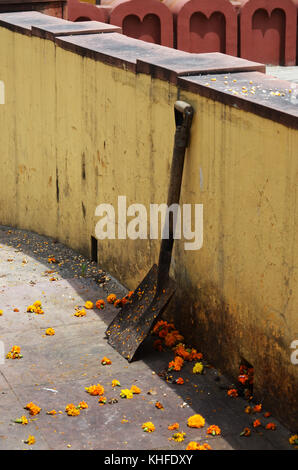 Petali di fiori e la pala appoggiata contro la parete a Nuova Delhi in India Foto Stock