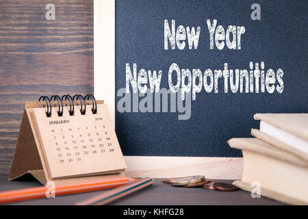 Anno nuovo nuove opportunità. calendario cartaceo e lavagna su una tavola di legno Foto Stock