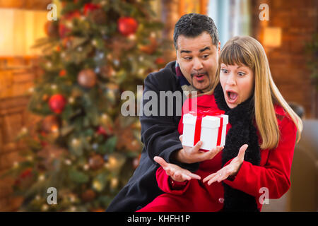 Razza mista giovane condivisione del natale di fronte decorate albero. Foto Stock