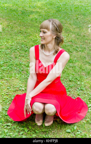 Bella signora in rosso sono seduti su quelle haunches Foto Stock