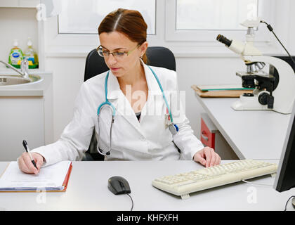 Medico che lavorano alla sua scrivania Foto Stock