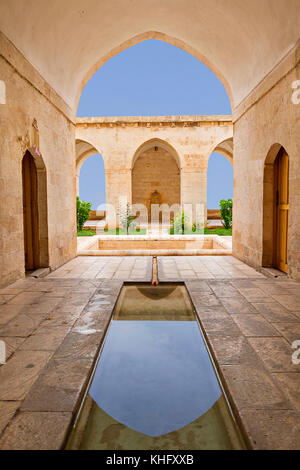 Antica scuola teologica conosciuta come Zinciriye Madrasah e riflessione nella sua piscina poco profonda nel suo cortile, a Mardin, Turchia Foto Stock