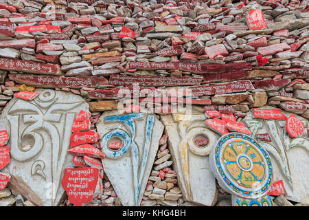 Yushu, Cina - 3 novembre 2017: Muro di pietre mani al tempio mani (mani Shicheng) con mantra buddista Om mani Padme Hum inciso in Tibetano i. Foto Stock