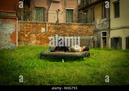 Dormire su una panchina in Venezia, hanno un pomeriggio snooz nei vicoli di Venezia, lo spazio verde con questa città giardino circondato da edifici Foto Stock