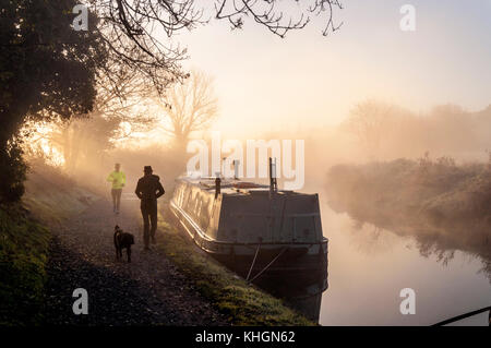 Bathampton, Somerset, Regno Unito meteo. 17 novembre 2017. Il sole sorge su narrowboats sul Kennet and Avon Canal su un gelido mattino luminoso. Per gli amanti del jogging e un dog walker sull'alzaia. Credito: Richard Wayman/Alamy Live News Foto Stock