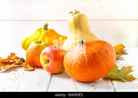 Zucca e Patty pan, mele e acero, rovere foglie gialle su una bianca tavolo in legno. raccolto autunnale Foto Stock