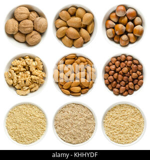 Le noci, le mandorle e le nocciole in bianco bocce. interi, decorticati e dadi di messa a terra. Prunus dulcis, corylus avellana, Juglans regia. macro foto di cibo. Foto Stock