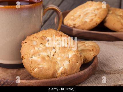 Primo piano di bianco dolci di cioccolato con nocciole di macadamia e tazza di caffè Foto Stock