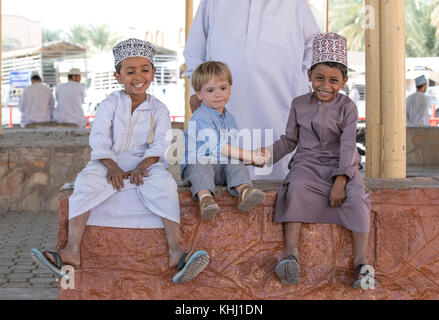 Nizwa, Oman, Novembre 10th, 2017: omani boys europea con un ragazzo in un mercato del venerdì Foto Stock