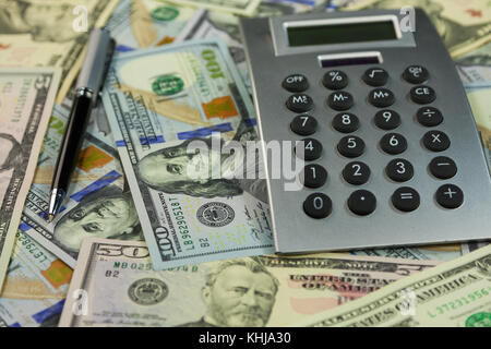 Calcolatrice e soldi si trovano sullo sfondo di dollari. Idee e concetti di business. Close-up Foto Stock